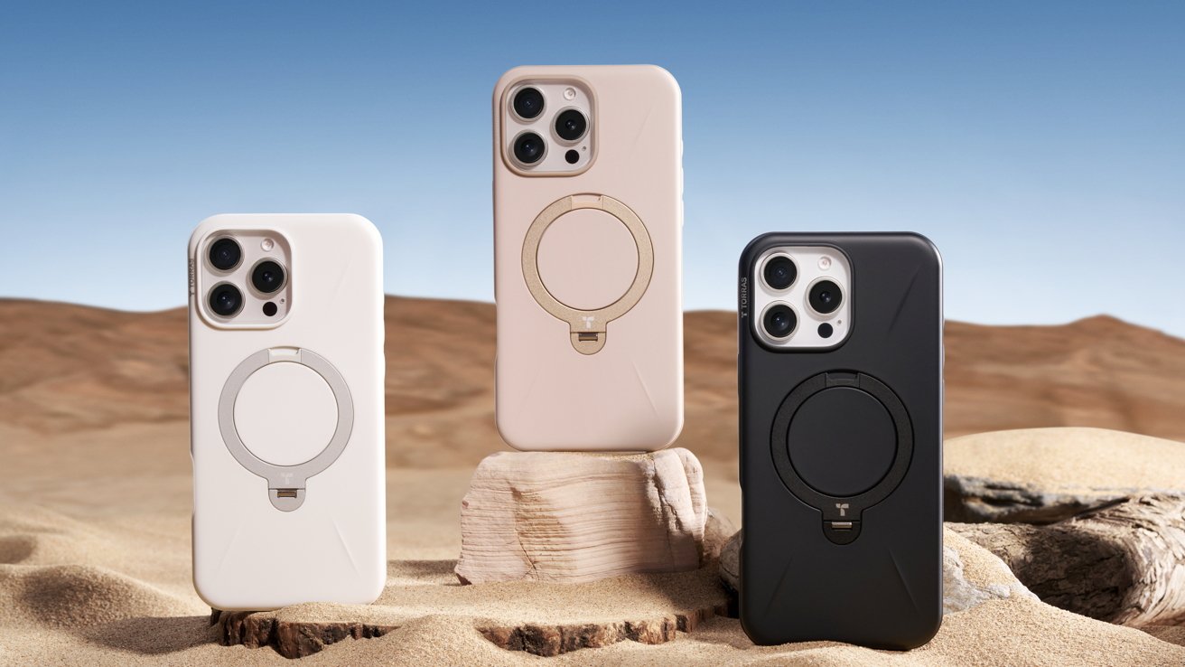 Three smartphones in protective cases stand on sandy desert terrain under a clear blue sky.