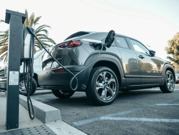 An image of an EV plugged in and charging in a parking lot.