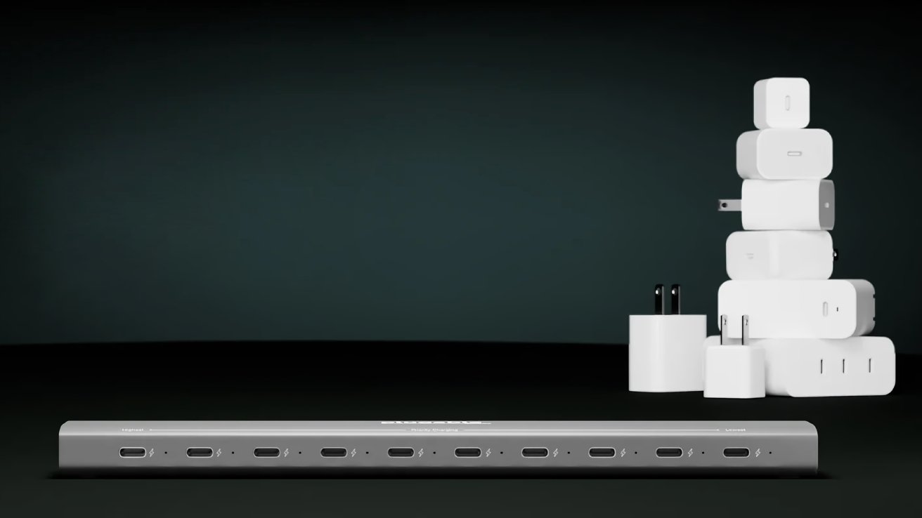 A row of USB-C ports on a sleek device with a stack of various white charging adapters in the background on a dark surface.