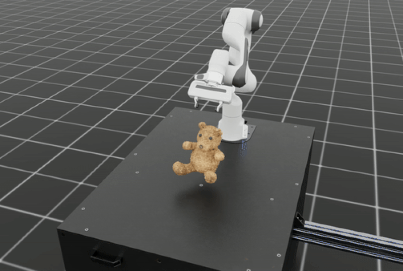 A white robotic arm manipulating a plush teddy bear on a black platform inside Isaac Sim.